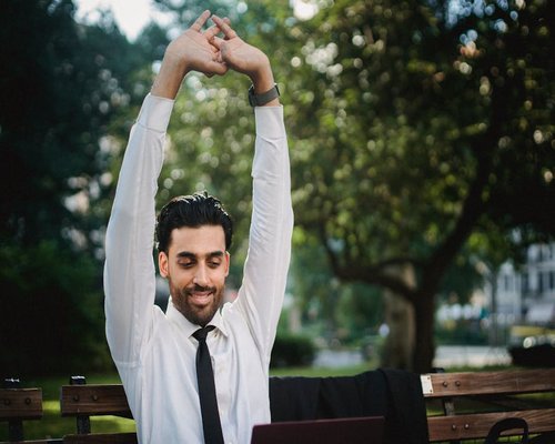Side view of a person stretching their arms over their head during a work break