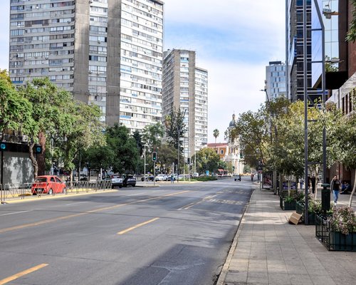 A quiet, sunny residential street in Chile with trees and sidewalk space for walking